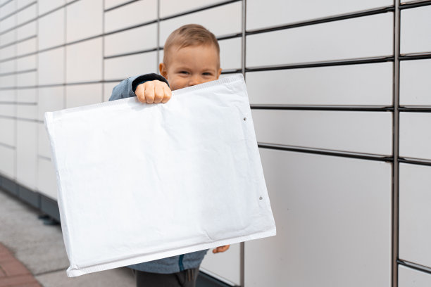 包裹投递，带储物柜的取件点，小孩拿包裹，非接触式包裹投递。儿童包裹，男孩使用自助包裹终端机发送或接收包裹图片下载