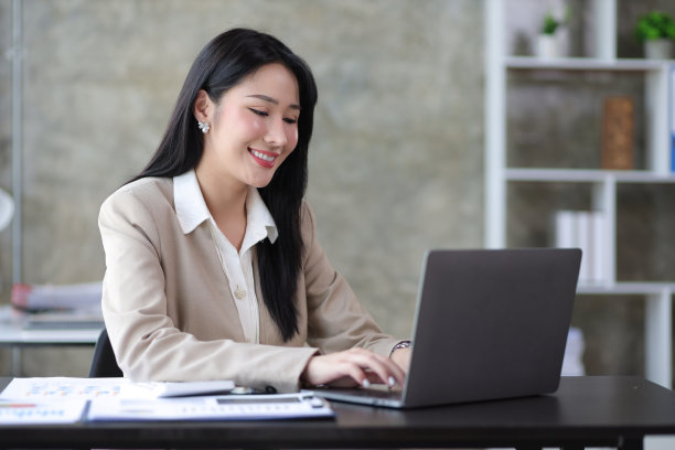 有吸引力的美丽的亚洲商业女性在办公室桌上的笔记本电脑上工作。图片下载