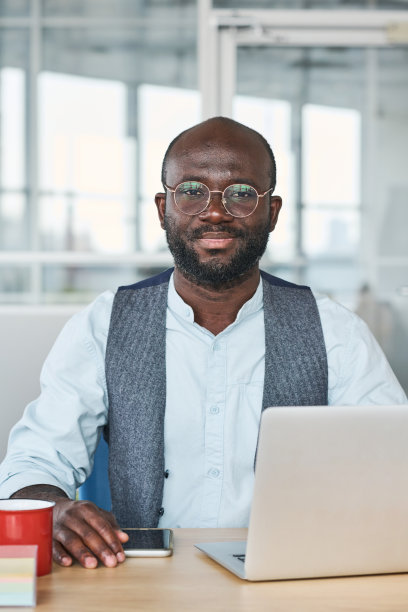 穿着正装的年轻成功上班族坐在笔记本电脑前图片下载