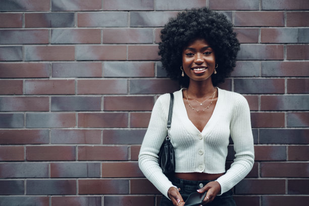 美丽的年轻非洲妇女在街上使用手机图片下载