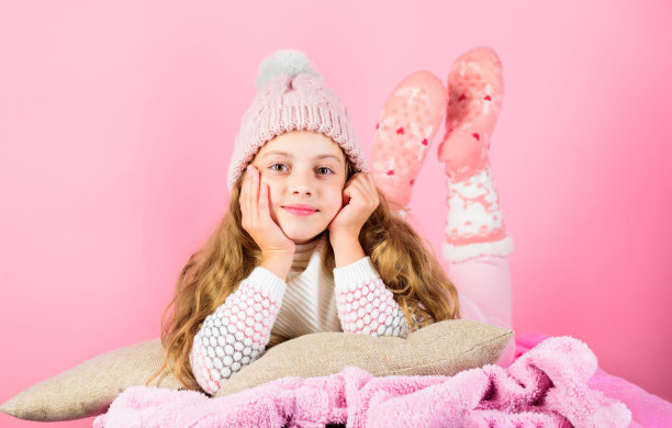 孩子做梦的脸戴针织配件。小女孩戴可爱的针织时尚帽子和围巾配件。冬天的时尚配件。冬季配件的概念。女孩长发梦粉色背景图片下载