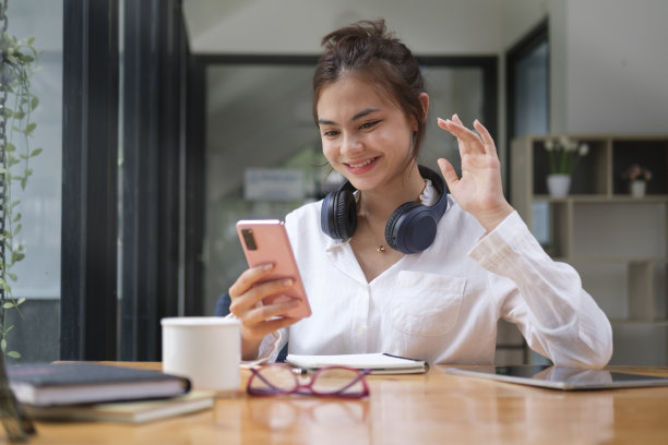 欢快的年轻女子挥手，用手机打视频电话。图片下载