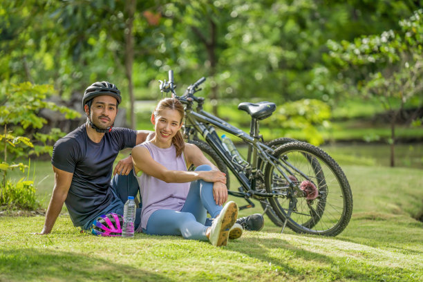 夏天，一对亚洲夫妇骑自行车锻炼后，一起在公园的湖边放松图片下载