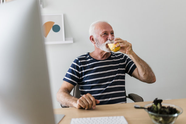 高级成年男子吃零食和工作在家里办公室图片下载