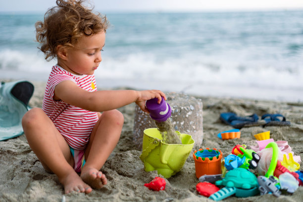 孩子正坐在沙滩上堆沙堡。图片下载