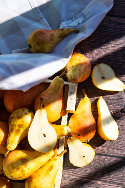 深色木桌上一个旧的乡村盒子里装着梨子。成熟的梨在盒子里。图片下载