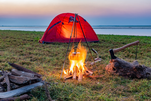 在湖边草地上的橙色帐篷里营火图片下载