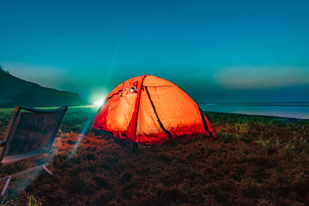 在湖边草地上的橙色帐篷里营火图片下载