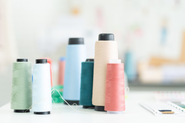 在裁缝店的桌子上有多种颜色的线。时尚、制衣的概念图片下载