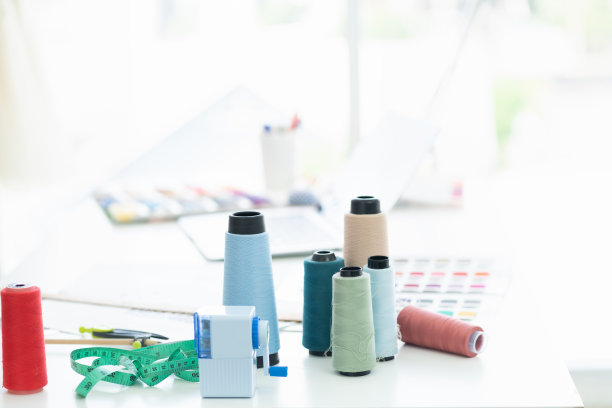 在裁缝店的桌子上有多种颜色的线。时尚、制衣的概念图片下载
