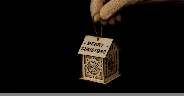 一间小木屋，在黑色的背景下，墙上有雕刻的铃铛和写着“圣诞快乐”的字样，看起来很漂亮。图片下载