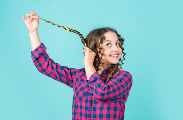 孩子的头发护理。小女人用卷发器梳理头发。美丽和时尚。小女孩有卷发器。孩子理发师沙龙。健康长发型。准备假期图片下载