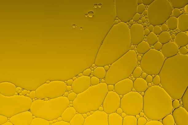 油和水的气泡在渐变的金色背景上创造艺术形象和图案。图片下载