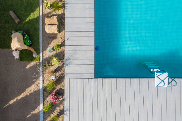 景观美化工人在游泳池周围安装天然草皮图片下载