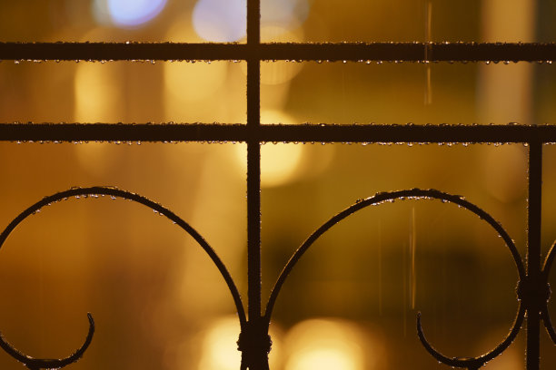 明亮的夜晚，金属栅栏上的水滴照片。图片下载