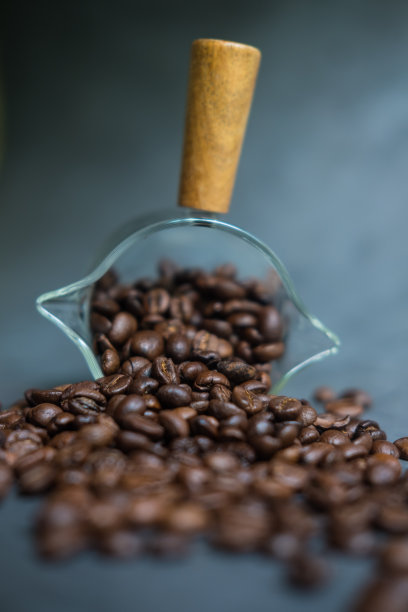 从透明玻璃杯中洒出的咖啡豆图片下载