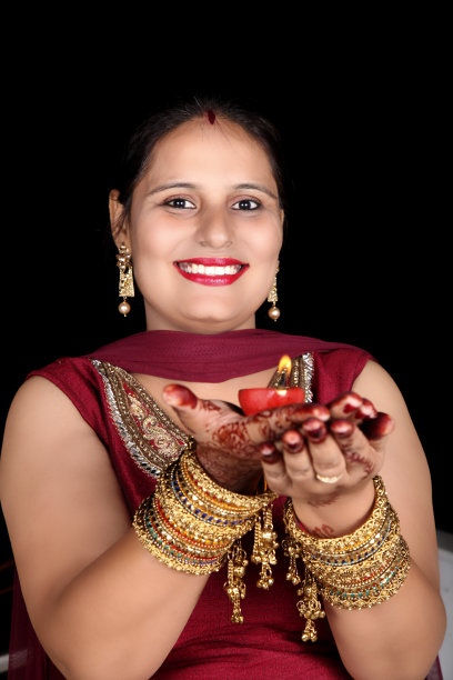 在karwa chauth节日期间，年轻的妇女带着露齿的微笑手持油灯在家里图片下载