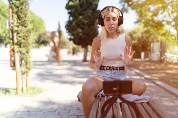 网红在公园长椅上向粉丝直播。社交媒体博主、数字内容创作者的概念。图片下载