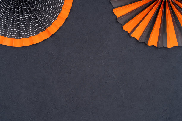 明亮的黑色和橙色的纸扇与条纹和点在黑色质感的背景。图片下载