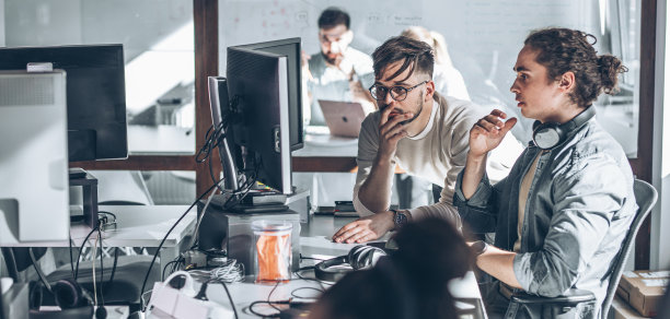 办公室里有两个程序员。他们讨论并致力于新项目。图片下载