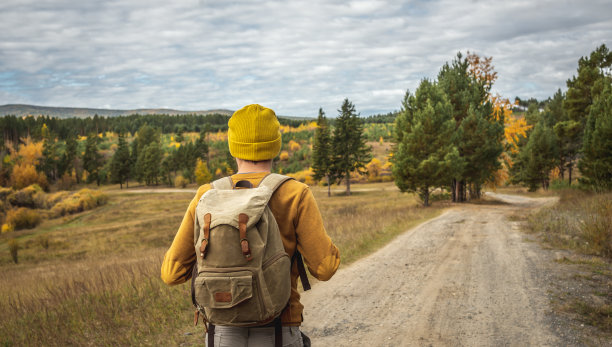 一个背着背包的旅行者走在一条空旷的森林小路上。自由的概念，旅行，远足和秋天的心情图片下载