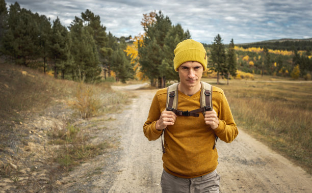 一个背着背包的旅行者走在一条空旷的森林小路上。自由的概念，旅行，远足和秋天的心情图片下载