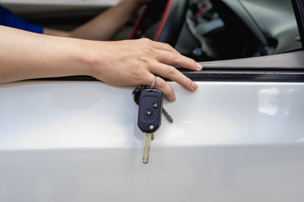 新车主把钥匙戴在手指上，放在车门上。图片下载