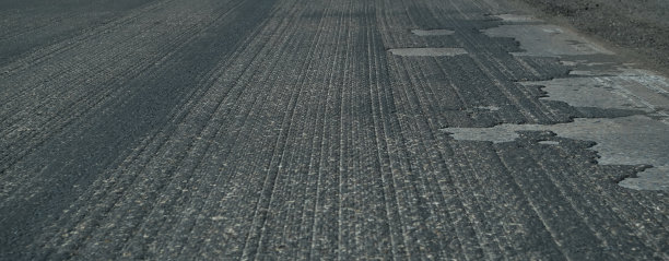 旧沥青。预算修路。森林里破碎的沥青。图片下载