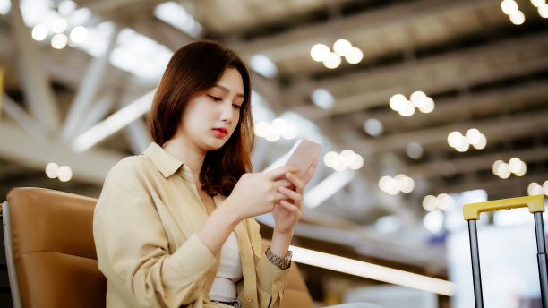 亚洲妇女在机场等待离开假期假期。亚洲女乘客坐在候机大厅用手机等机图片下载