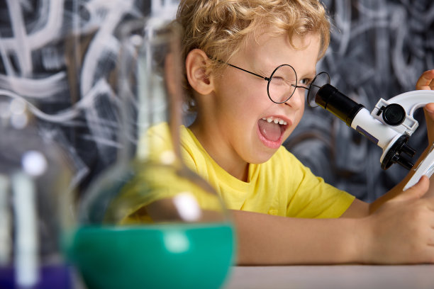 孩子仔细地看着放在桌子上方的显微镜目镜图片下载