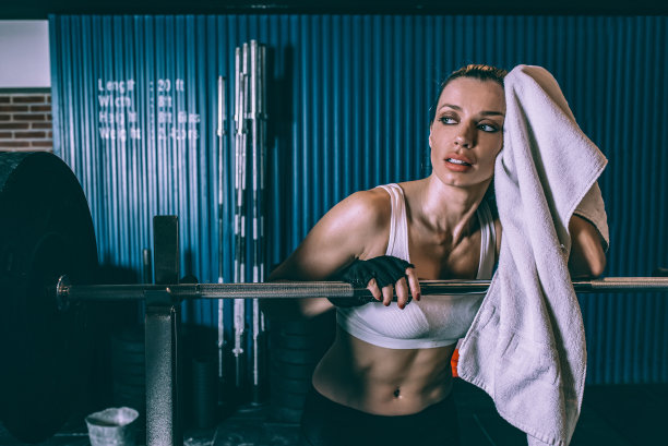 健身金发女人休息后训练举重在健身房的杠铃图片下载