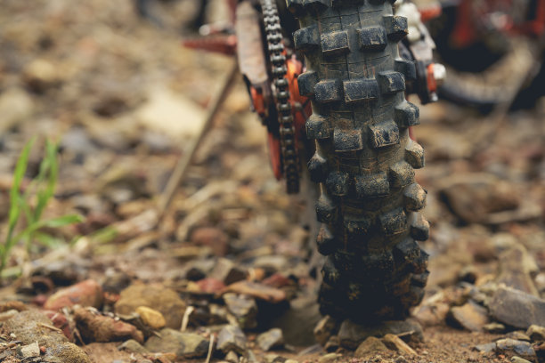 部分摩托车越野车轮上的岩石道路，与复制空间为您的个人文本。森林里一辆土路摩托车的一部分。图片下载