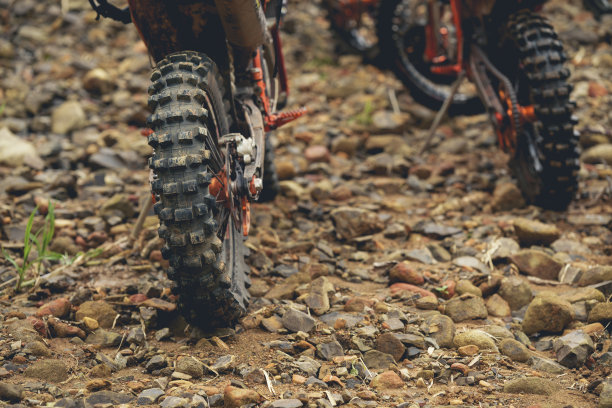 部分摩托车越野车轮上的岩石道路，与复制空间为您的个人文本。森林里一辆土路摩托车的一部分。图片下载