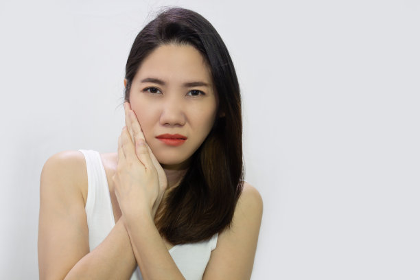 亚洲美女摸她的脸颊和牙疼和疼痛，有一个高度敏感的牙齿。图片下载