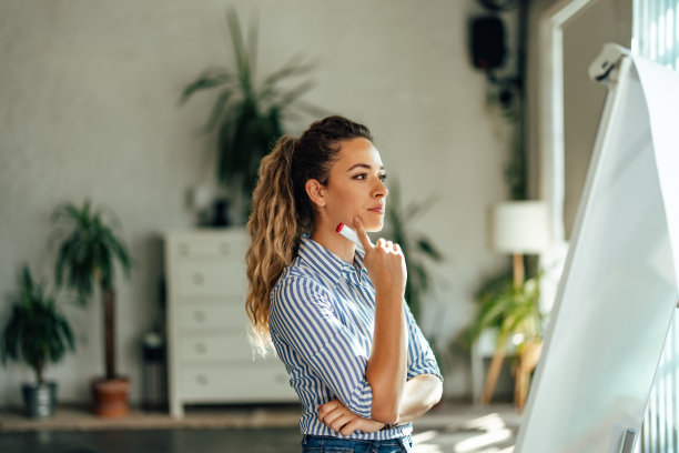 专注的女孩看着白板，手里拿着马克笔。图片下载