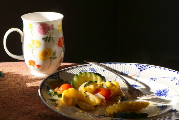餐桌上有蔬菜盘和花图案的杯子图片下载
