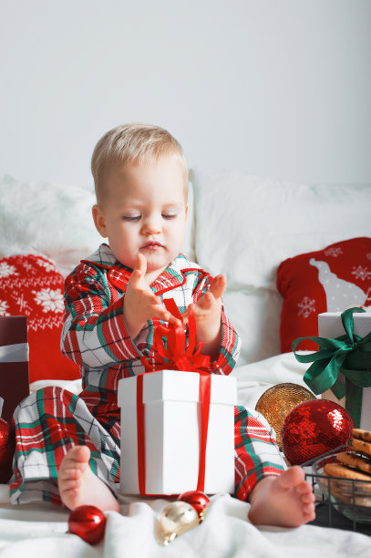 可爱的蹒跚学步的男孩穿着睡衣和圣诞礼物在家里特写。新年家里的舒适，卧室的装饰。图片下载