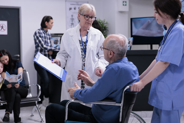 高级医生与使用轮椅的退休人员洽谈预约事宜图片下载