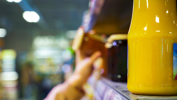 模糊的背景:一个女人的手从架子上拿了一罐果冻。图片下载