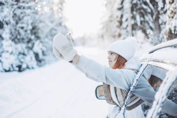 十几岁的女孩在冬天的雪林里旅行，看着车窗外，用智能手机自拍。自驾游和本地旅游的概念。快乐的孩子享受汽车旅行。图片下载