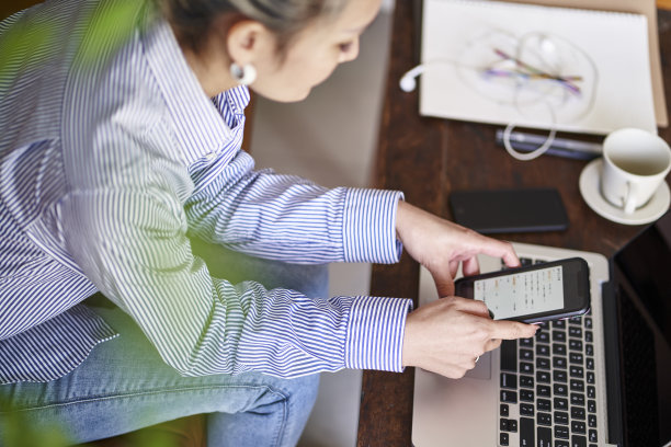 成熟的亚洲女性在家使用手机和笔记本电脑工作图片下载