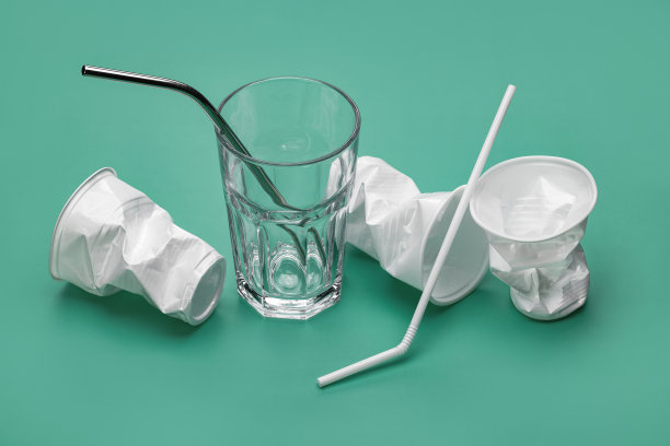 用吸管喝水的玻璃杯和皱巴巴的塑料玻璃杯。图片下载