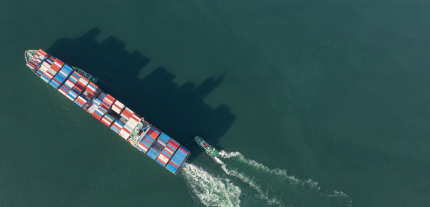 拖轮将集装箱货物智能船拖至国际集装箱堆场港口概念海运。图片下载