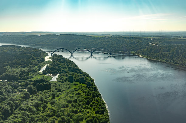 从飞机窗口拍摄的航拍照片。夏日夕阳下，飞机飞过有桥的河图片下载
