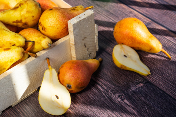 深色木桌上一个旧的乡村盒子里装着梨子。成熟的梨在盒子里。图片下载