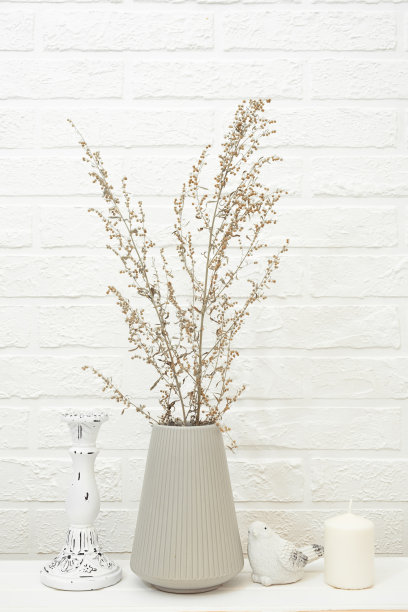 花束干草枝在现代灰色陶瓷花瓶和装饰项目在白桌子对白砖墙。斯堪的纳维亚风格中中性色调的极简构图。图片下载