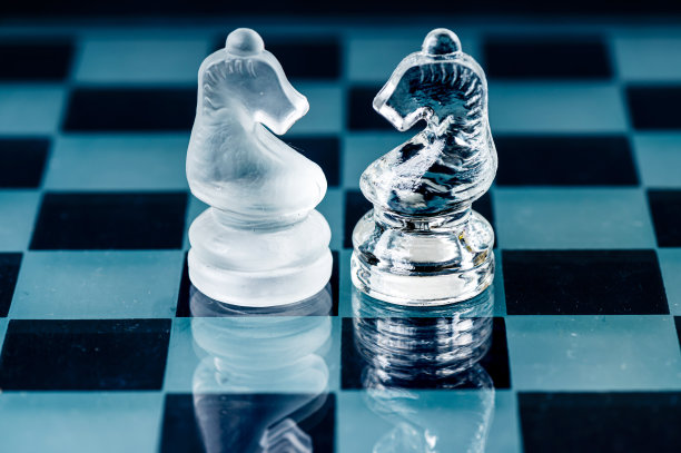 两个对手玻璃象棋骑士在一个玻璃棋盘上，黑色背景图片下载