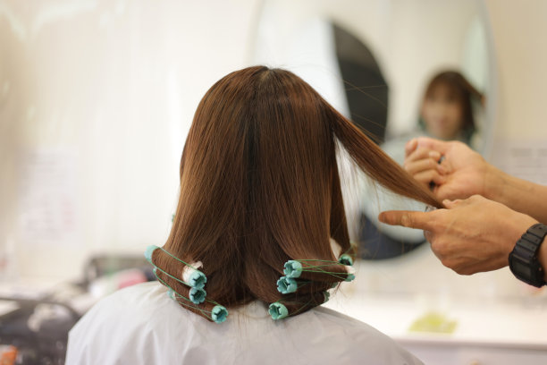 男理发师在女人的头发上绕着烫发棒图片下载