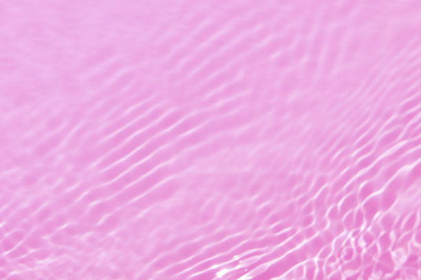 离焦模糊透明的粉红色颜色清澈平静的水面纹理与水花、气泡。闪亮的粉色水波纹背景。游泳池的水面。热带粉红色的水色流动。图片下载