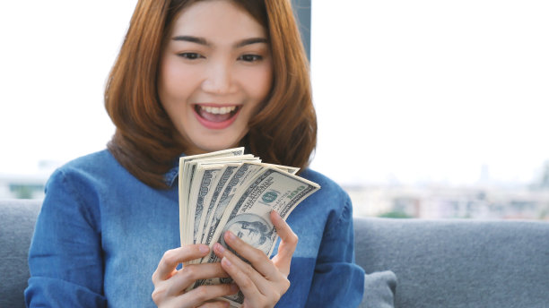 快乐的年轻亚洲女子拿着美元钱，抛向空中庆祝幸福舞蹈财富彩票钱雨滴。成功者成功的商人女人扔现金流快乐的钱笑脸图片下载